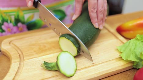 Women's-hands-Housewives-cut-with-a-knife-fresh-zucchini-on-the-cutting-Board-of-the-kitchen-table